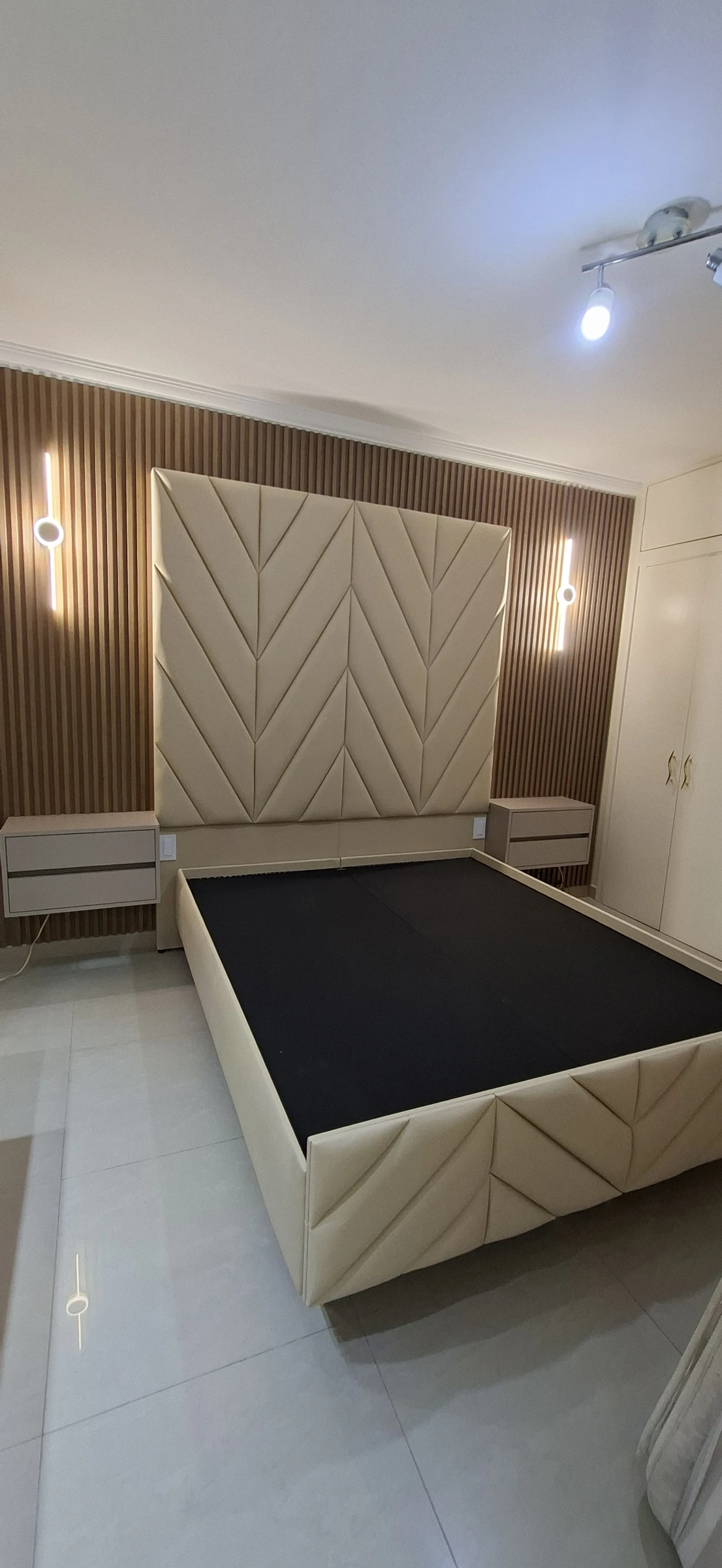 Cabecero geométrico tapizado, base de cama y mesas flotantes en una instalación real de ESTUDIO 243